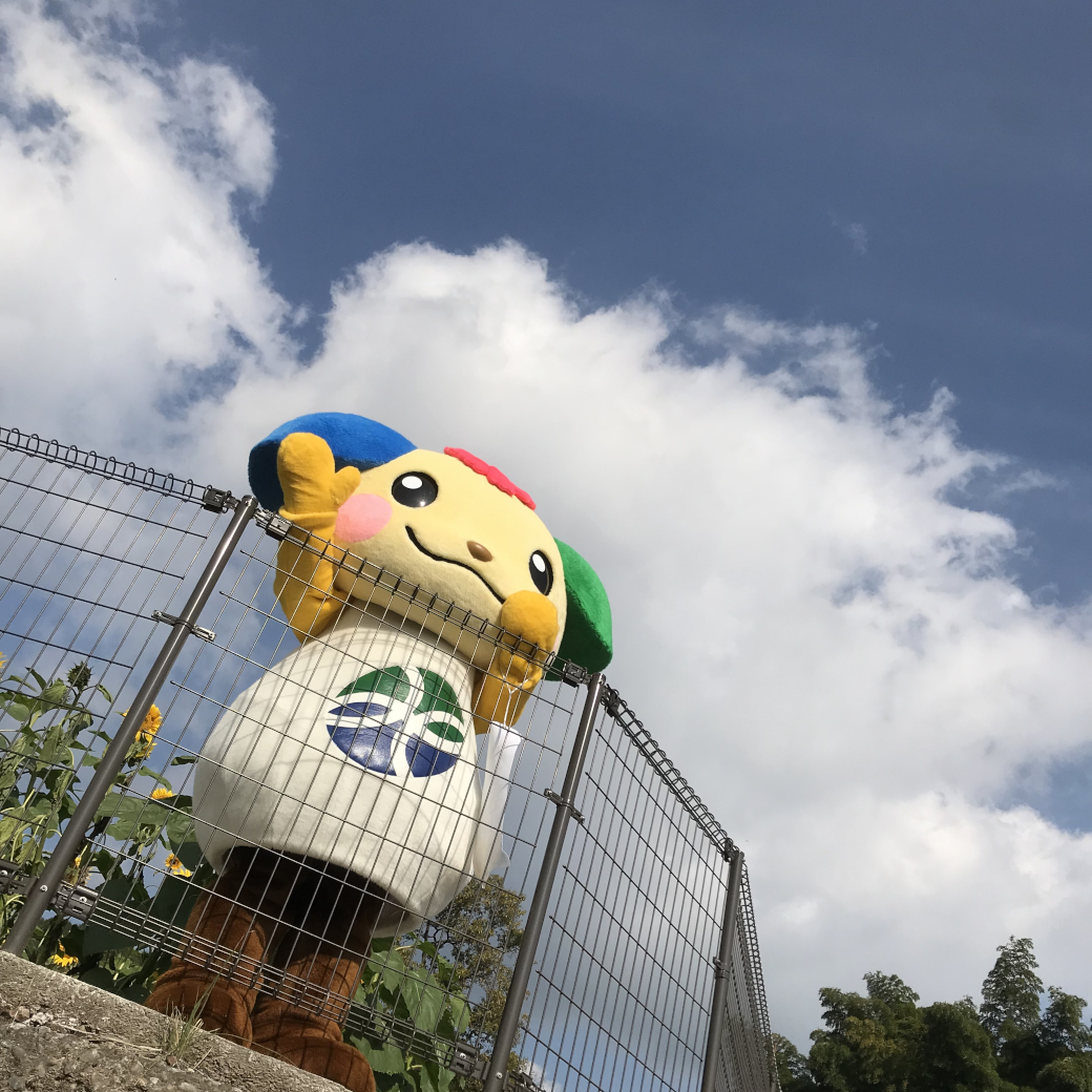 青空の下で手を振るご当地キャラ・みやっきー
